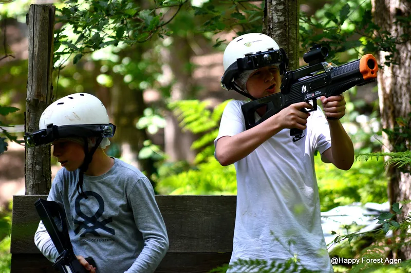 Deux enfants casqués jouent au laser game en forêt à Happy Forest