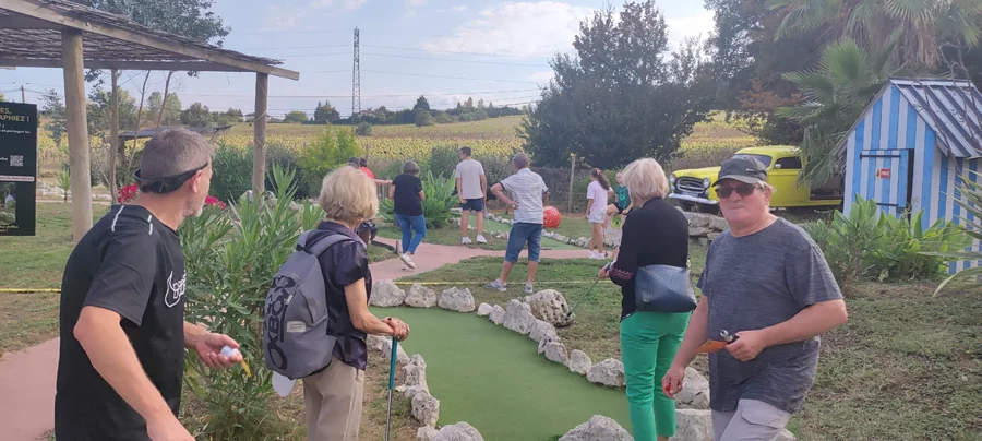 Visiteurs jouant au mini-golf paysager de Happy Forest, avec vue sur les champs de tournesols