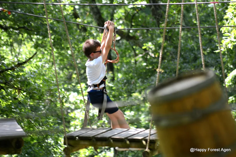 Enfant en tyrolienne au-dessus du parcours accrobranche de Happy Forest